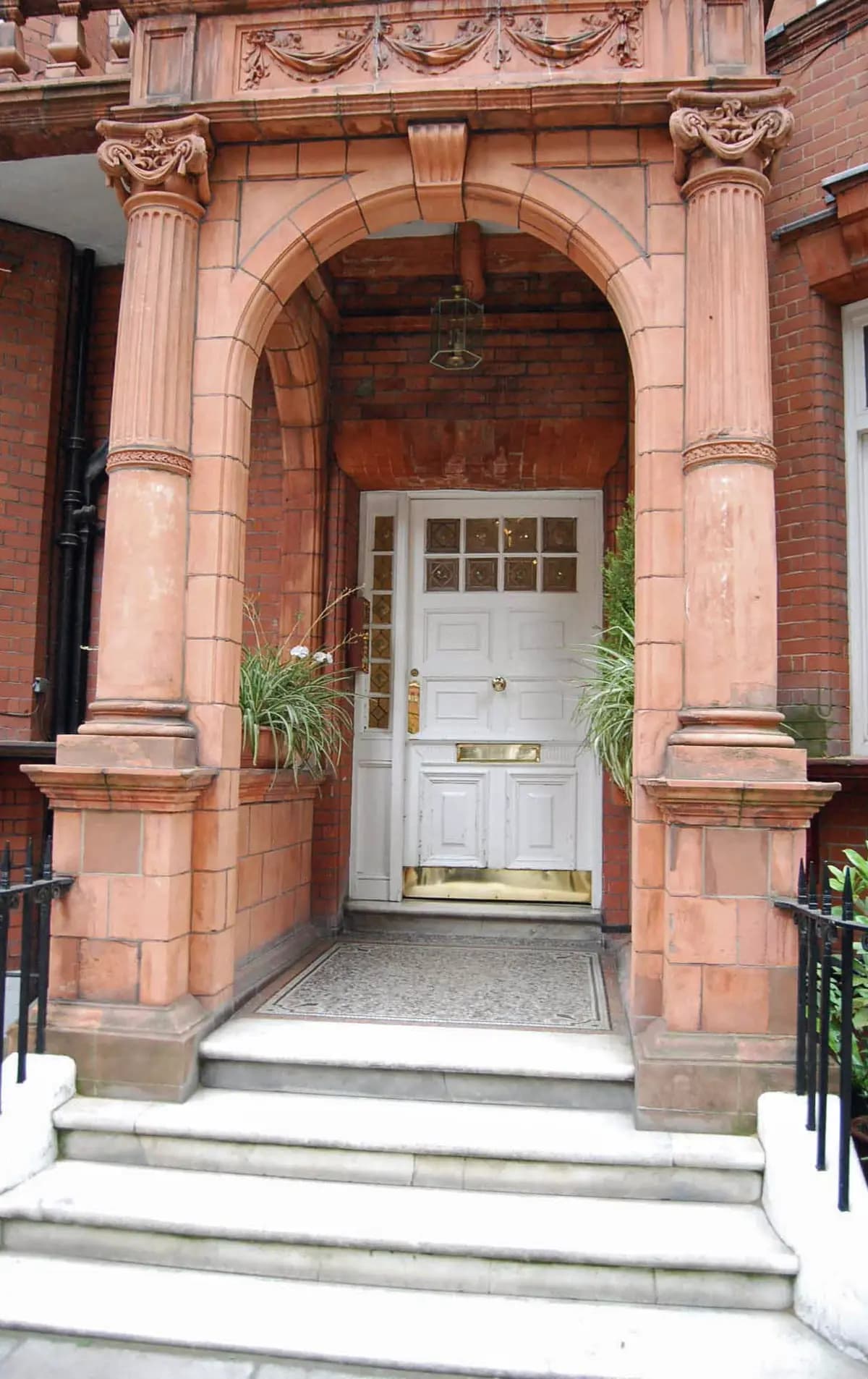 A terracotta arched porch leading to a white panelled front door in London