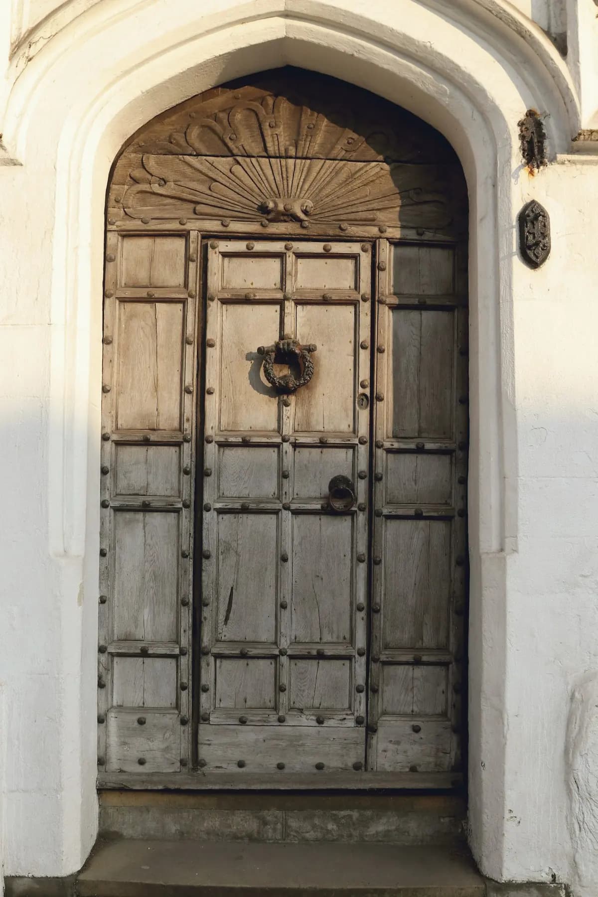 An old wooden door within a whitewashed pointed arch