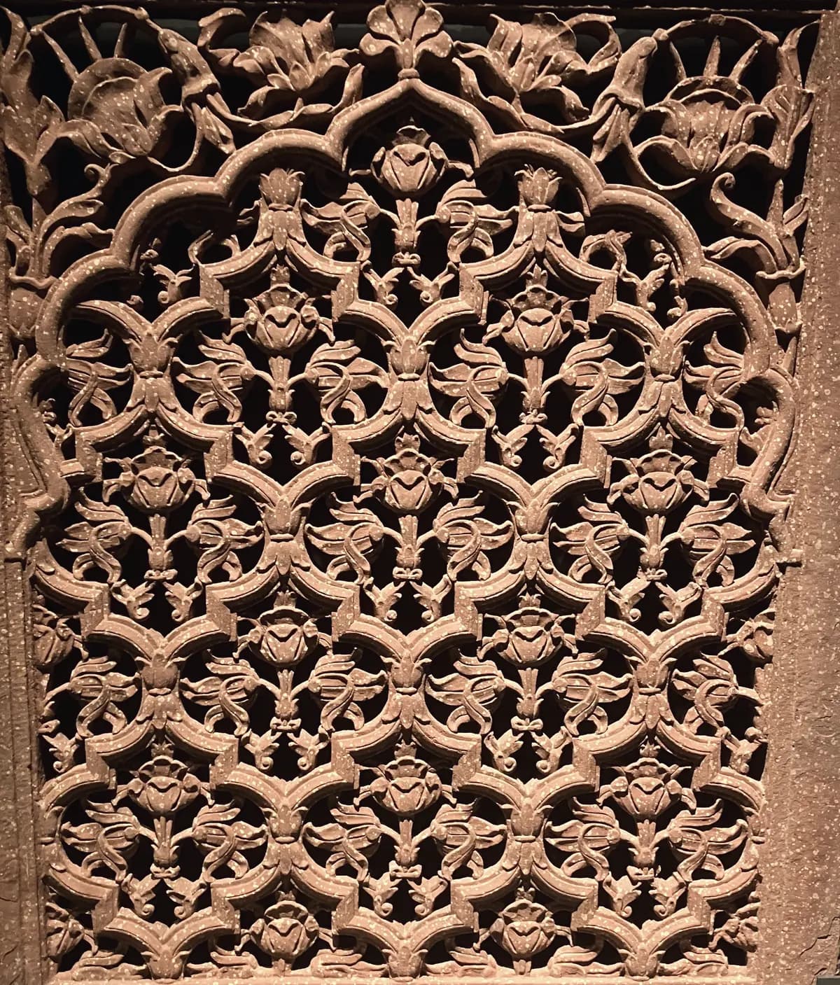 A carved red sandstone jali screen, its floral lattice open to the light